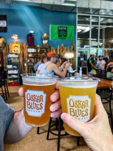 Two beers toasting at Oskar Blues