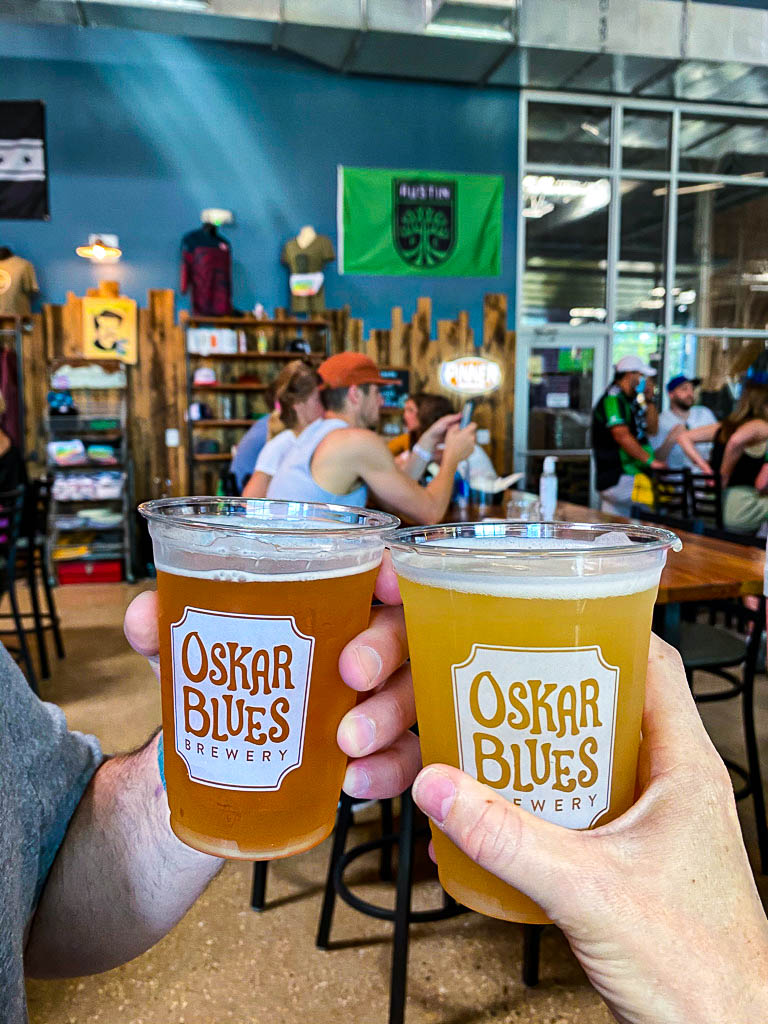 Two beers toasting at Oskar Blues